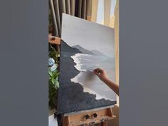 a person is painting on an easel in front of a window