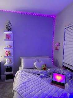 a laptop computer sitting on top of a bed in a room with purple walls and lights