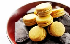 a red bowl filled with yellow and black macaroons on top of some rocks