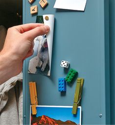 a person holding a roll of paper over a magnet board with legos on it