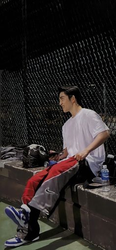 a man sitting on top of a bench next to a fence