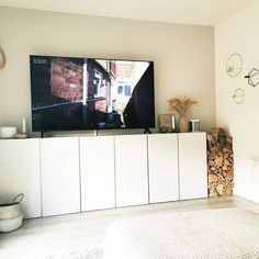 a flat screen tv sitting on top of a white cabinet next to a fire place