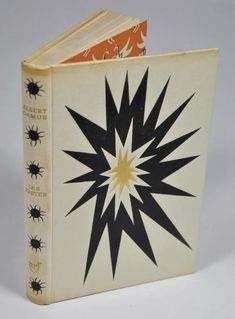 an old book with black and yellow designs on it's cover, sitting on a white surface