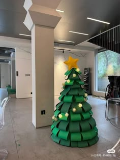 a large christmas tree made out of green paper in an office space with chairs and tables