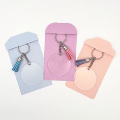 three tags with tassels attached to them on a white surface, one has a key chain and the other has a bottle opener