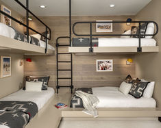 two bunk beds in a room with wooden walls and white carpeted flooring, along with black metal ladders that lead up to the second bed