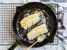 two pieces of fish cooking in a skillet