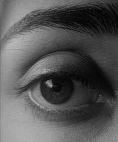 the eye of a woman with long eyelashes and black hair is seen in this black and white photo