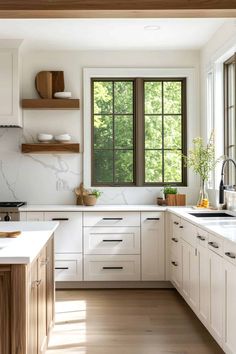 a kitchen with white cabinets and wood floors is pictured in this image, there are two windows above the sink