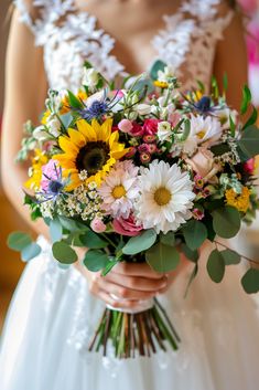 a bride holding a bouquet of sunflowers and greenery on her wedding day