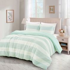 a bed in a bedroom with green and white striped comforter on top of it