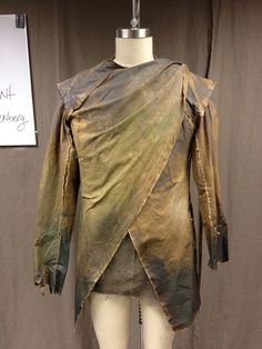 a mannequin is dressed in an old leather jacket and dress with gold paint on it