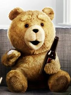 a brown teddy bear holding a beer bottle on top of a couch with other stuffed animals