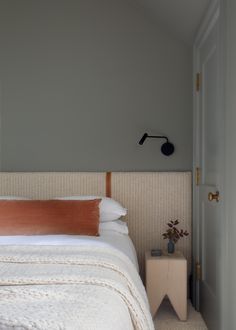 a white bed sitting next to a door in a bedroom