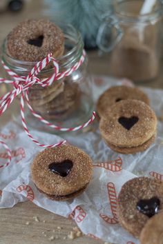 small cookies with chocolate in the middle are sitting on wax paper and tied to glass jars