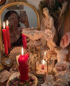 a woman taking a selfie in front of a mirror with candles and seashells