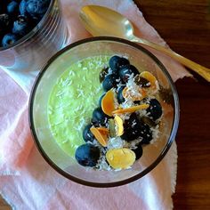 a bowl filled with blueberries and oranges on top of a pink napkin next to a spoon