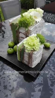 two square cakes with flowers and ribbons on top of a black tablecloth covered outdoor dining area