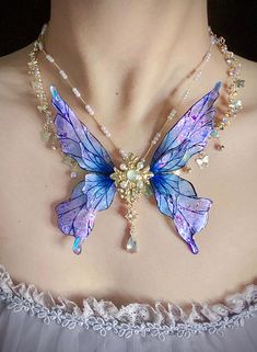 Step into a world of enchantment with our breathtaking Fairy Wing Necklace! This exquisite handcrafted piece captures the ethereal beauty of fairy magic in a wearable work of art. * Handcrafted iridescent butterfly wings that shimmer with every movement * Mesmerizing purple and blue hues that shift in the light * Intricate, hand-drawn wing patterns making each piece uniquely artisanal * Elegant gold accents, including a central floral medallion * Delicate chain with small decorative elements Art Purple Fairy Wings, Wings Accessories, Enchanted Butterfly, Fantasy Jewelry Magic, Iridescent Butterfly, Elements Art, Blue Butterfly Wings, American Makeup, Ethereal Jewelry