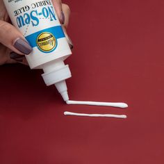 a hand holding a bottle of toothpaste with two white sticks sticking out of it