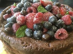 a chocolate cake topped with fresh berries and minty sprinkled powdered sugar