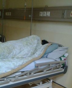 a hospital bed with white sheets and blankets on it's sides in a room