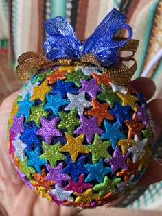 a hand holding a colorful ornament with stars on it