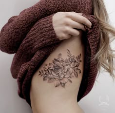 a woman with a flower tattoo on her left side ribcage is holding onto the arm