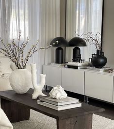 a living room with white furniture and black vases on the coffee table in front of it