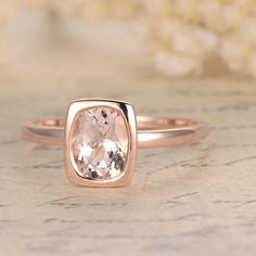 an engagement ring with a pink morganite stone in the center on a marble surface