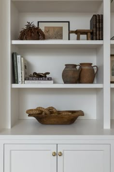 a white book shelf filled with books and vases