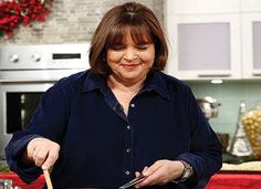 a woman is cooking in the kitchen with a large skillet and wooden spatula