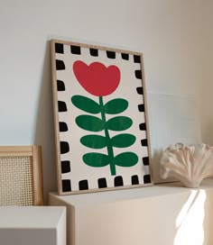 a painting with a red flower on top of a shelf next to a white wall