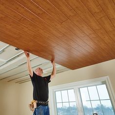 a man is working on the ceiling in an empty room