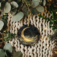 a ceramic ornament hanging from a tree filled with green leaves and greenery