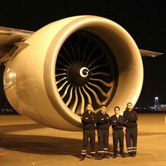 three men standing in front of an airplane engine