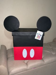 a cardboard box with mickey mouse's ears on it sitting on top of a couch