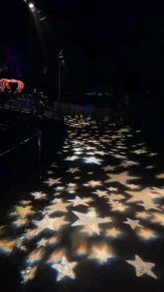 an image of stars on the ground at night with street lights in the dark behind them