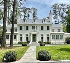 a large white house surrounded by trees and grass