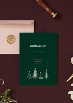 a green christmas party card on top of a table next to a envelope and pen