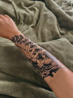 a person's arm with a tattoo on it sitting on top of a bed