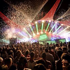 a large group of people standing in front of a stage with confetti all over it