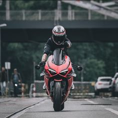 a man riding on the back of a red motorcycle