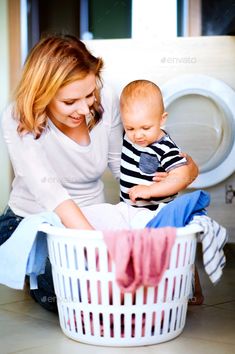 a woman and baby sitting in front of a washing machine