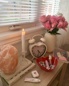 a table topped with pink flowers next to a white clock and other personal care items