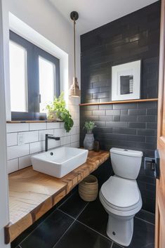 a white toilet sitting next to a sink in a bathroom under a window on top of a wooden counter