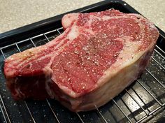 a piece of raw meat sitting on top of a metal grill grates in front of it