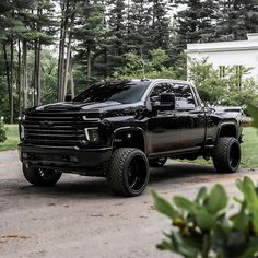 a black truck is parked in front of some trees