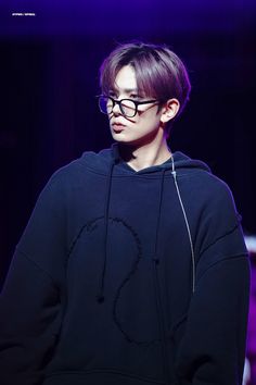 a young man wearing glasses and a hoodie on the runway at a fashion show