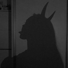 the shadow of a man with horns on his head is shown in black and white